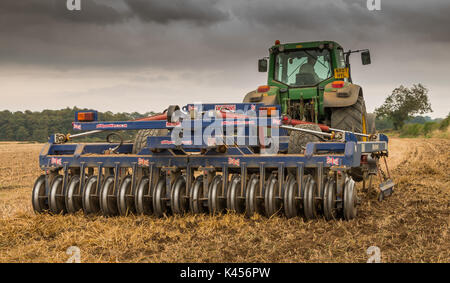 Großbritannien Landwirtschaft - 4 meter Philip Watkins Falten gezogenen drücken und John Deere 7530 Traktor bei der Arbeit die Kultivierung eines Feldes von Weizen zur Kontrolle der Schnitthöhe Stockfoto