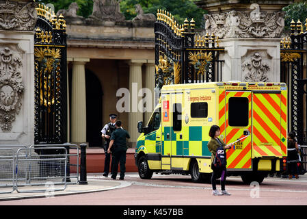 NHS-Krankenwagen kommt am Buckingham Palace, London, UK Gate mit bewaffneter Sicherheitspolizei an. Touristen fotografieren mit Selfie-Stick Stockfoto