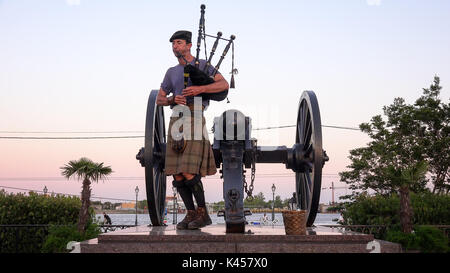 Mann im Kilt Dudelsack spielen neben der Kanone auf Sonnenuntergang an der Jackson Square im französischen Viertel von New Orleans, Louisiana Stockfoto