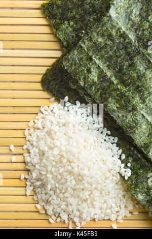 Grüne nori Blatt und Sushi Reis auf Bambus Matte. Ansicht von oben. Stockfoto