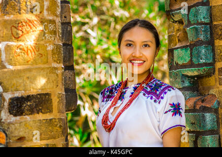 QUITO, ECUADOR - August, 30 2017: Porträt einer jungen indigenen Frau trägt einen typisch andinen Kleidung, für Kamera vor einer alten Mauer Posing, im Park Stockfoto