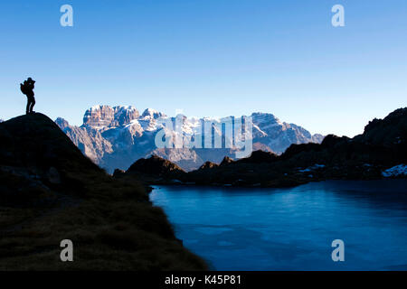 Europa, Italien, Südtirol, Trient, Val Nambrone Tal, Brenta Dolomiten, cornisello Seen. Der Lago Nero See und Cima Tosa Alp mit Wanderer Silhouette im Winter. Stockfoto