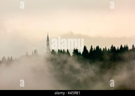 Kirche, Roana, Hochebene von Asiago in der Provinz Vicenza, Venetien, Italien. Turm im Nebel. Stockfoto