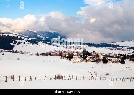 Stadt, Hochebene von Asiago in der Provinz Vicenza, Venetien, Italien. Farbige Häuser in Winterlandschaft. Stockfoto