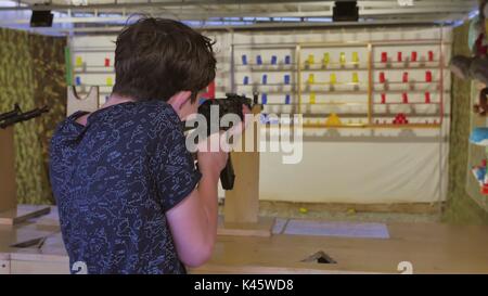 Junge Teenager schießt in einem Bindestrich aus dem Maschinengewehr. Luftpulser Gewehr. Junge lifestyle Gun Stockfoto