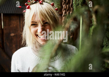 Blonde Frau, Kopfschmuck, Girlande mit Hagebutten, Zweige von Evergreens für Dekoration, Spaß, Porträt, Stockfoto