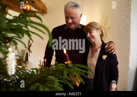 Senior Paar vor Weihnachtsbaum, halb Portrait Stockfoto