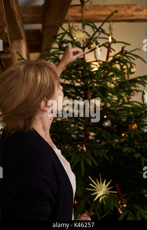 Frau leuchten Kerzen am Weihnachtsbaum, Heiligabend Stockfoto