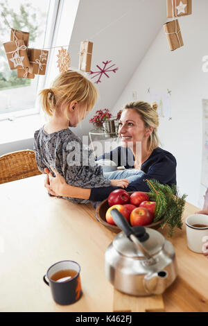 Mutter und Tochter mit Adventskalender, am Küchentisch sitzen, Stockfoto