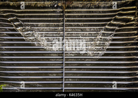 Entwässerung Wasser strömen an einem Entwässerung metal Grill der Entwässerung Fach auf Bürgersteig Stockfoto