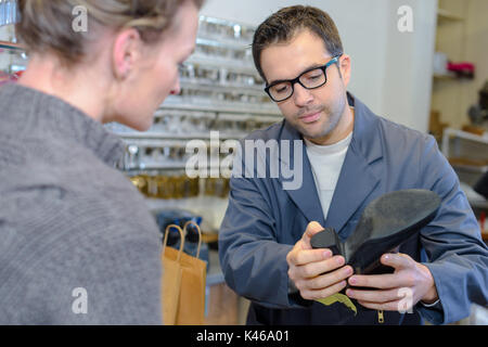 Schuster im Gespräch mit Kunden abouit Schuhe ferse Stockfoto