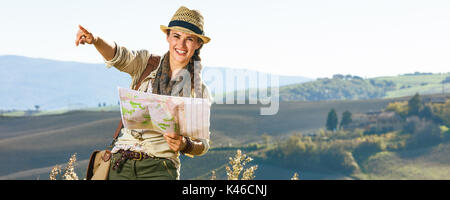 Entdecken Sie magische Ausblicke der Toskana. glückliche junge Frau Wanderer mit Tasche auf der Toskana Wanderung mit Karte und zeigen Stockfoto