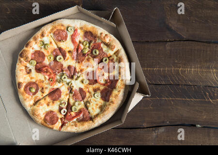 Blick von oben auf die köstliche frische Pizza im Karton auf Holz- Tabelle Stockfoto