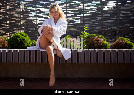 Junge lächelnde Frau im Bademantel auf der Terrasse eines Luxus Hotels Stockfoto