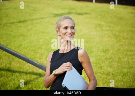 Close up Portrait von Happy reife Frau mit Laptop mit dem Grün im Hintergrund. Stockfoto
