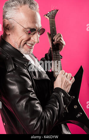 Freudige stilvolle älterer Mann in Sonnenbrille Spielen von Rock und Roll Musik mit E-Gitarre Stockfoto