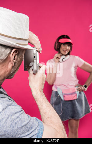 Selektiver Fokus der Mann die Bild der Frau isoliert auf Rosa Stockfoto