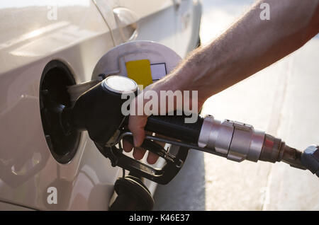 Hand, die Kraftstoffpumpe und das Befüllen mit dem Auto an der Tankstelle Stockfoto