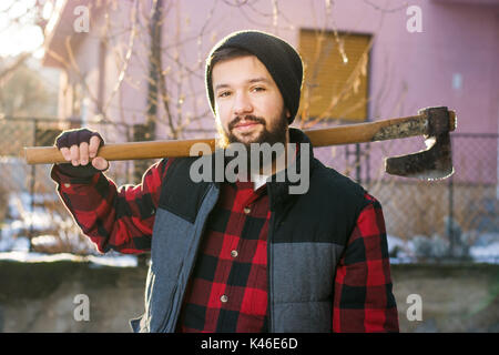 Maskulinen Mann mit einer Axt zum Schneiden von Brennholz im Hof Stockfoto