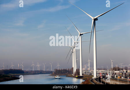 Industrie und Windkraftanlagen in der Nähe von Canal Hartel im industriellen Bereich Europoort von Rotterdam in den Niederlanden. Ein binnenschiff und Lkw im Hintergrund. Stockfoto