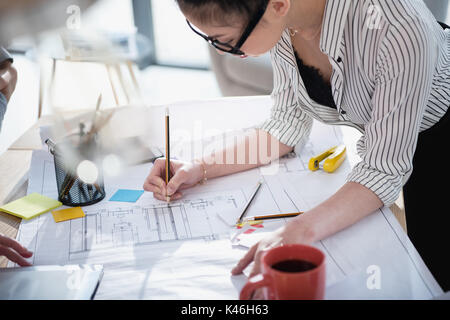 Jungen asiatischen Geschäftsfrau in Brillen arbeiten mit Blueprint im Büro Stockfoto