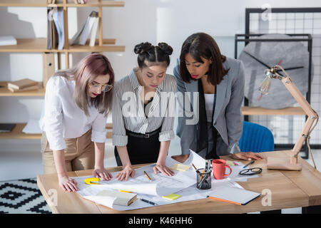 Jungen multiethnischen Designer auf der Suche nach Baupläne im Amt stehende Stockfoto