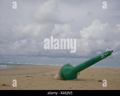 Grün navigation Boje, gewaschen, die auf einem leeren Strand an einem kalten grauen Tag im Westen von Frankreich. Stockfoto