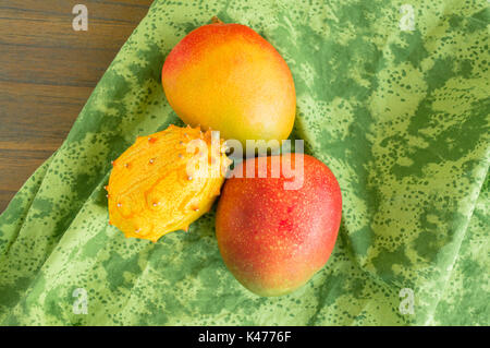 Mangofrüchte und kiwano Melone isoliert auf ein grünes Tuch von oben gesehen Stockfoto