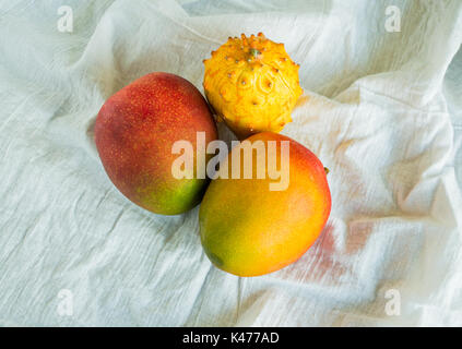 Mangofrüchte und kiwano Melone isoliert auf ein weißes Tuch von oben gesehen Stockfoto