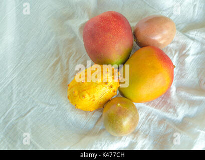 Mango, Passionsfrucht, Melone auf einem weißen Tuch gesehen von oben Stockfoto