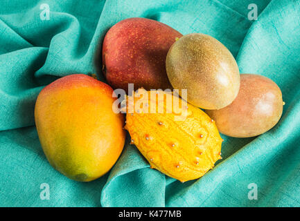 Mango, Passionsfrucht und kiwano Melone auf grünem Tuch gesehen von oben Stockfoto