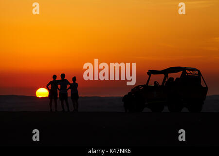 Dune Buggy und Touristen beobachten die Sonne über Sanddünen in der Wüste in der Nähe von Huacachina Oasis, Ica, Peru, Südamerika (MR) Stockfoto