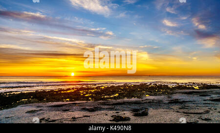 Sun Einstellung unter orange Himmel über dem Horizont auf den Atlantischen Ozean von Camps Bay in der Nähe von Kapstadt Südafrika an einem schönen Wintertag Stockfoto