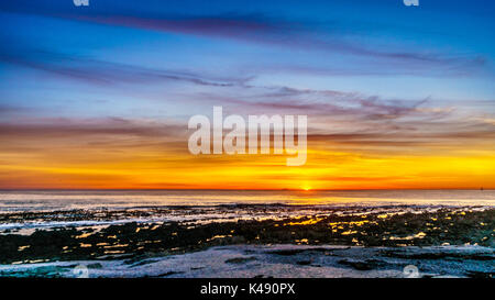 Sun Einstellung unter orange Himmel über dem Horizont auf den Atlantischen Ozean von Camps Bay in der Nähe von Kapstadt Südafrika an einem schönen Wintertag Stockfoto
