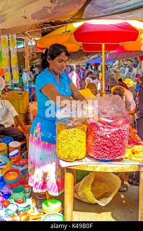 WELLAWAYA, SRI LANKA - Dezember 2, 2016: Die Frau Verkäufer in kleinen Snack stall Angebote Muttern in Gewürzen und süße Nüsse in großen Plastiktüten, am 2. Dezember Stockfoto