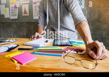 Männer arbeiten als Fashion Designer beschließen, auf die Farbkarte für Kleidung in der digitalen Tablet am Arbeitsplatz studio Stockfoto