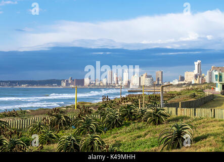 Der frühe Winter morgen Dünenvegetation Strand und Meer am Strand gegen den blauen bewölkten Himmel und Durban Skyline der Stadt in Südafrika Stockfoto