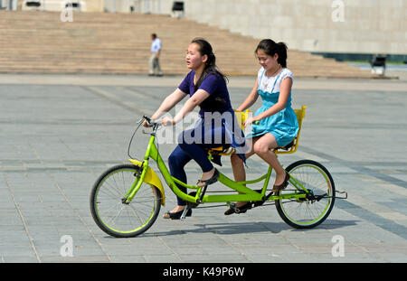 Zwei Mädchen, ein Fahrrad auf Dschingis Khan Square, Ulaanbaatar, Mongolei Stockfoto