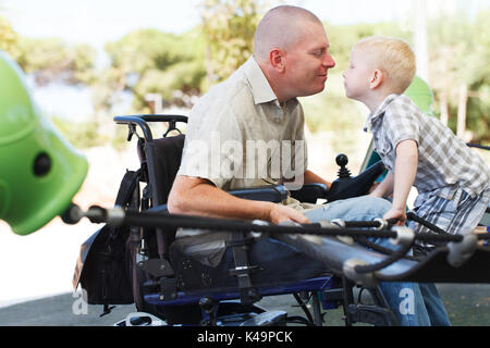 Behinderten Vater spielen mit kleinen Sohn auf dem Spielplatz Stockfoto