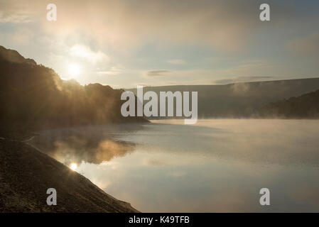 Atemberaubende September Morgen bei Ladybower Reservoir, Peak District, Derbyshire, England. Nebel über der Wasseroberfläche treiben. Stockfoto