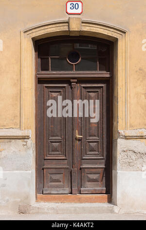Alten, braunen Tür auf einem Gebäude mit gelben Wänden und mit der Hausnummer über der Tür Stockfoto