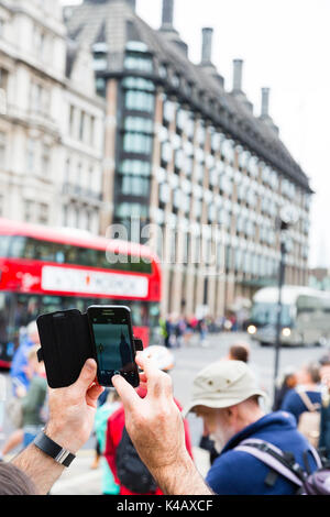 London, Großbritannien. Ein Mann nimmt ein Foto von Big Ben mit einem fotohandy am Parliament Square. Stockfoto