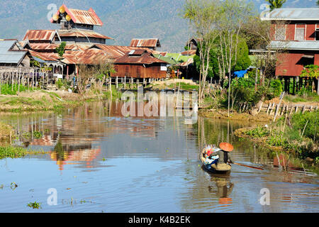 Alte Häuser und ihre Reflexion und Boot segeln zwischen ihnen im Wasser auf dem Inle See, Myanmar Stockfoto