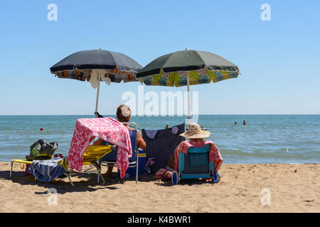 Zwei Badenden genießen Sie den Sandstrand zu bleiben unter dem Dach Stockfoto