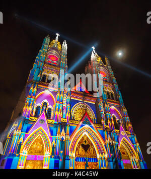 QUITO, ECUADOR - August 9, 2017: Schöne Aussicht bei Nacht der neo-gotischen Basilika der Nationalen Gelübde mit bunten Lichtern während der Quito licht Festival beleuchtet, mit einem vollen Mond im Himmel Stockfoto