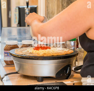 Vorbereitung eines französischen Snack bestehend aus einem salzigen Krepp, auch als "galete" bekannt. Dieses ist mit Käse und Tomaten Sauce kann aber auch süße wi. Stockfoto