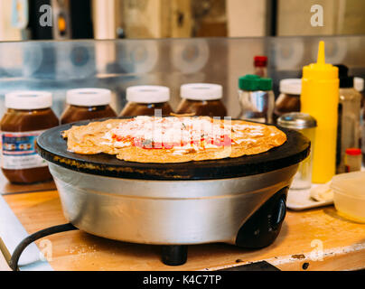 Vorbereitung eines französischen Snack bestehend aus einem salzigen Krepp, auch als "galete" bekannt. Dieses ist mit Käse und Tomaten Sauce kann aber auch süße wi. Stockfoto