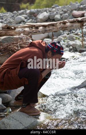 Berber Mann trinken aus Fluss, setti Fatma Markt, ourika Tal, Marokko Stockfoto