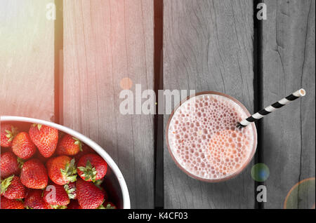 Ein Glas Erdbeer Milch auf einem Holztisch Stockfoto