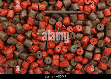 Angeln Köder mit Haken und Braun mit roten vorgebohrte Heilbutt Pellets für Karpfen angeln Hintergrund Stockfoto